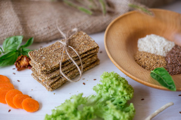 Crispbread tightened by a rope. Healthy food on a white background besid the ingredients in a wooden plate. .Lettuce with carrot near bread cakes