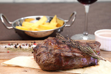 Medium-roasted steak cut into pieces on a wooden board with sauce and seasonings. Delicious steak. Beef steak medium rare on vegetable cushion. Beef steak on wooden plate. 