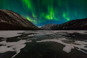 Fototapeta na wymiar Snow-capped mountains at night under the northern lights. Norway.