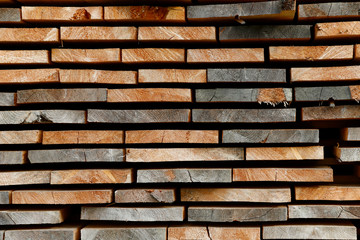 Background texture saw cut planks of hard wood. Drying boards in the open air. Close-up, horizontal, cropped shot, free space. Construction and woodworking concept.