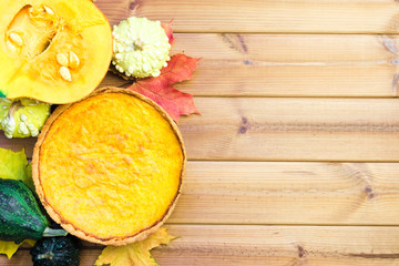 Festive wooden table with pumpkin pie, decorative pumpkins and maple leaves. Happy thanksgiving day concept
