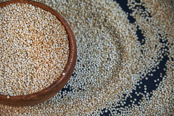 White quinoa seeds on a black background. quinoa in bowl on kitchen table top view. Healthy and diet superfood product.