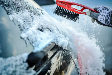 Cleaning snow from car window. Removing snow from windshield.