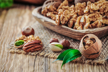 Nuts mixed in wooden bowl. Nuts on wood table with color background