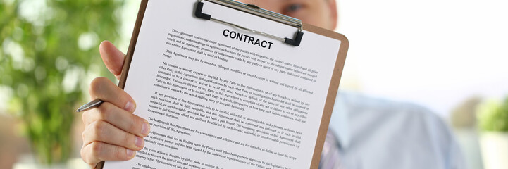 Male arm in suit offer contract form on clipboard pad and silver pen to sign closeup. Strike a bargain for profit white collar motivation union decision corporate sale insurance agent concept