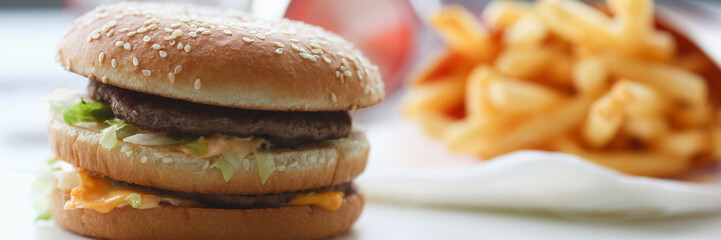 Hamburger and french fries with headphones lay on the desktop in the office during lunch break food delivery concept