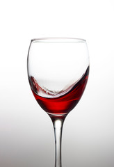 Splash of red wine in a crystal glass on a white background close-up