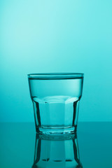 Glass cup with water on a blue background close-up