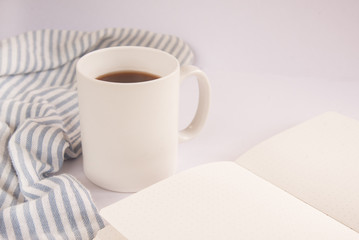 White office desk table with blank notebook page with cup of coffee. A white Cup of coffee and book on a white background. Workplace writer or freelancer. copy space.