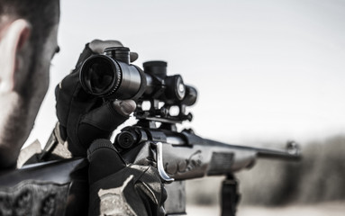 Hunter with hunting gun and hunting form to hunt. Hunter is aiming. Shooter sighting in the target. The man is on the hunt. Hunt hunting rifle. Hunter man. Hunting period. Close up. Black and white