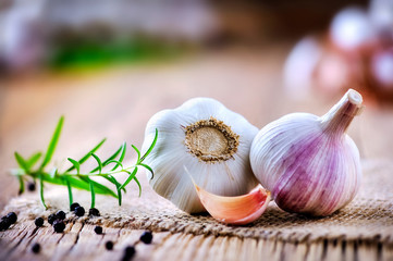 Garlic cloves on wooden table with jute. Fresh garlic bulbs and peeled violet garlic and black pepper.