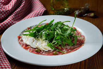 Fresh Vitello tonnato (dish of cold, sliced veal) with arugula and parmesan mushrooms on white plate. Close up view. Italian cuisine. Food photo background.
