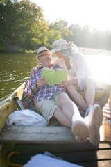 Wife hugging husband while chilling in boat and reading