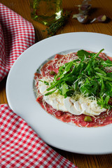 Fresh Vitello tonnato (dish of cold, sliced veal) with arugula and parmesan mushrooms on white plate. Close up view. Italian cuisine. Food photo background.