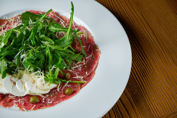 Fresh Vitello tonnato (dish of cold, sliced veal) with arugula and parmesan mushrooms on white plate. Close up view. Italian cuisine. Food photo background.