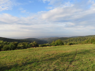 Fototapeta na wymiar Green fields and distant hills landscape in the autumn