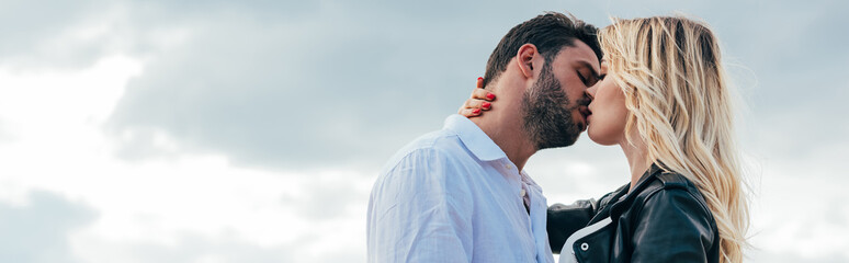 panoramic shot of attractive woman and handsome man kissing outside