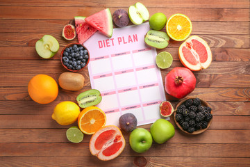 Different healthy food with diet plan on wooden table