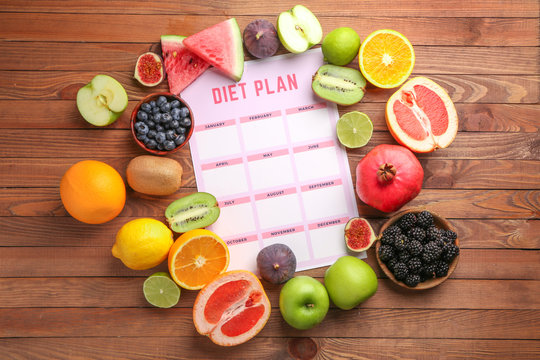 Different healthy food with diet plan on wooden table