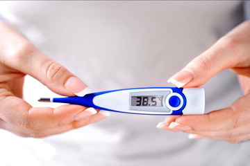 Thermometer in woman hands with french nails.. Digital thermometer shows high temperature. Sickness and ill concept.
