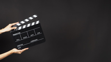 Hand is holding  black clapper board or movie slate or clapperboard. It is use in video production , movie ,film, cinema industry on black background.