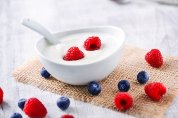 yogurt with forest fruits in white porcelain bowl. Yogurt with raspberries and blueberries.