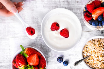 Top view on yogurt with forest fruits. Raspberries, blueberries and strawberries in bowls on white table.