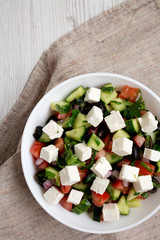 Homemade Shepherd's salad with cucumbers, feta and parsley in a white bowl, view from above. Flat lay, top view, overhead.