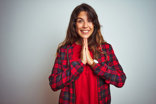 Young beautiful woman wearing red t-shirt and jacket standing over white isolated background praying with hands together asking for forgiveness smiling confident.