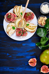 Bruschetta and Crostini with pear, ricotta cheese, honey, figs, nuts and herbs. Breakfast toasts or snack sandwiches. Antipasto. Italian food. Top view. Copy space.