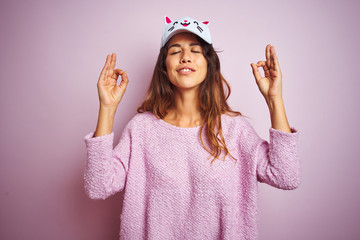 Young beautiful woman wearing funny cat cap standing over pink isolated background relax and smiling with eyes closed doing meditation gesture with fingers. Yoga concept.