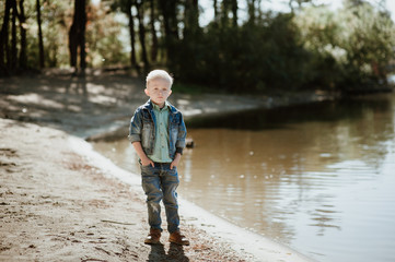 Portrait of cute smiling boy on a summer riverbank.