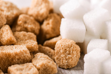 Brown sugar cubes on white rustic table. Pile of white sugar cubes.