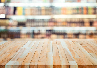 Wood table top on blur of drinking product shelf background in  supermarket or grocery background