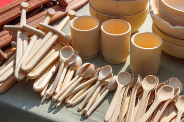 The variety of wooden products lying on the table - spoons, cups and child toys