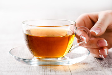 Woman holding a glass cup of black tea. Hot tea in beautiful cup with woman fingers and perfect french nails.
