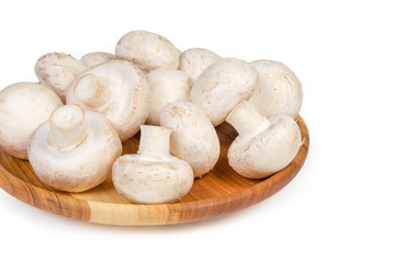 Cultivated button mushrooms on the wooden dish close-up
