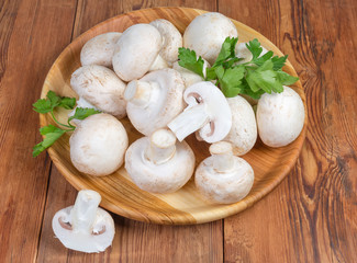 Cultivated button mushrooms on the wooden dish on rustic table