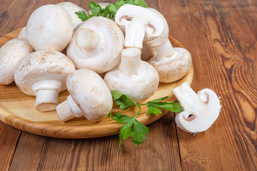 Cultivated mushrooms on wooden dish on rustic table close-up