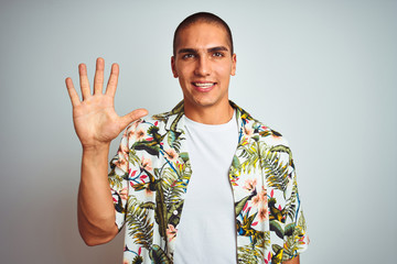 Young handsome man on holidays wearing Hawaiian shirt over white background showing and pointing up with fingers number five while smiling confident and happy.