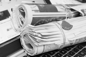 Newspapers and laptop. Pile of daily papers with news on the computer. Pages with headlines,...