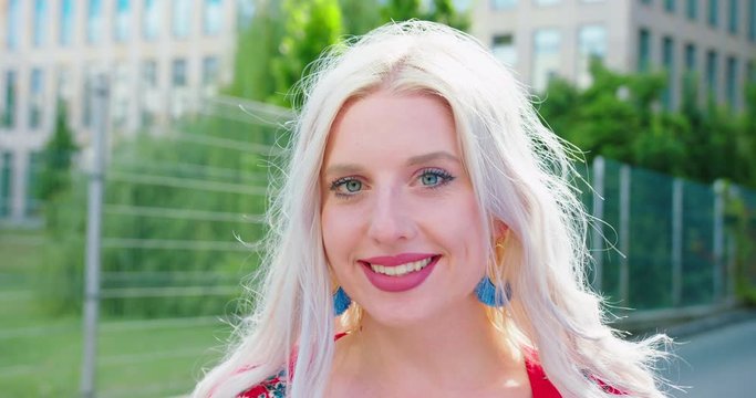 A young blonde lady smiling outdoors