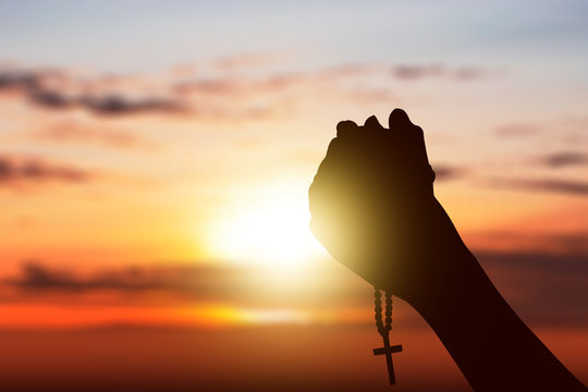 Human hands with rosary beads raised while praying to god