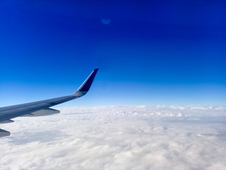 Obraz premium Wing of the plane on blue sky background. Airplane Wing in Flight from window, blue sky. Travel concept idea.