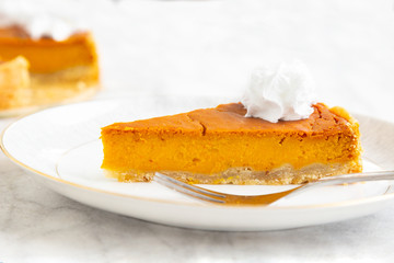 Slice of vegan homemade pumpkin pie with vegan whipped cream