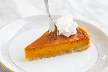 Slice of vegan homemade pumpkin pie with vegan whipped cream