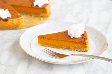 Slice of vegan homemade pumpkin pie with vegan whipped cream