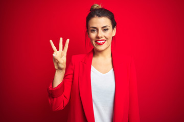 Young beautiful business woman standing over red isolated background showing and pointing up with fingers number three while smiling confident and happy.
