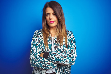 Young beautiful woman wearing a jacket standing over blue isolated background skeptic and nervous, disapproving expression on face with crossed arms. Negative person.