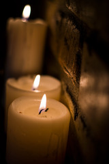 Background or texture of large white burning candles in dark room near brick wall. Holiday. Helloween.